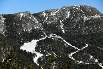View to Cliff House Restaurant at top of Mt. Mansfield Vermont at Stowe ski resort. Late spring time with snow on the mountains and blue sky.