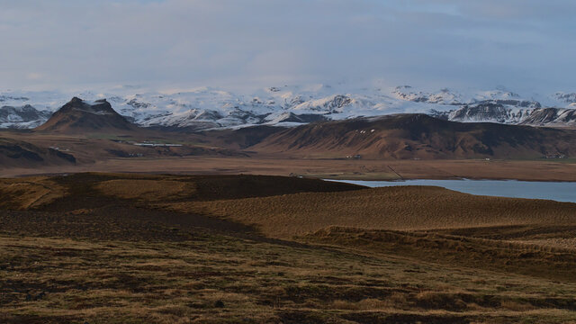 Stunning panoramic view of the snow-covered rugged foothills of Mýrdalsjökull glacier, covering volcano Katla, in evening sunlight viewed from Dyrholaey peninsula on the south coast of Iceland. © Timon
