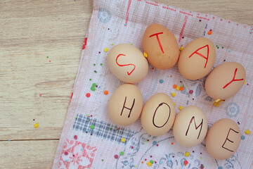 Chicken eggs with the words "stay home" lie on the towel. Spreading for glaze on the background. Easter preparation.