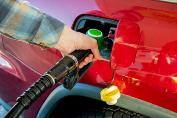 A man hand holding pump filling gasoline into the car. Pumping petrol into the tank. A car refuel on gas station