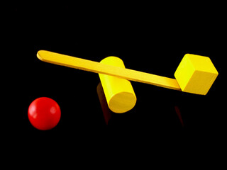 Conceptual image with colorful objects where the cube has outweighed a ball.