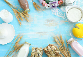 Top view photo of dairy products over blue wooden background. Symbols of jewish holiday - Shavuot