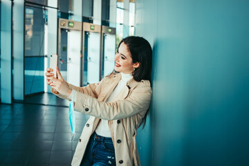 Cute girl is holding a medical mask in her hand and taking selfies with smartphone during pandemic of Coronavirus Covid-19