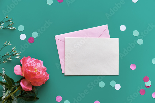 Mother's day greeting card design with pink peony flower on green mint, turquoise paper background. with paper confetti, text space. Trendy casual arrangement, top view. Summer birthday, anniversary.