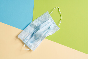 A crumpled protective mask lying on the colorful background in the studio