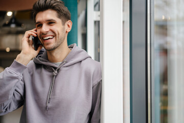 Happy young brunette man holding mobile phone