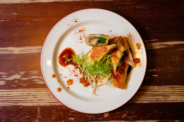 Spring rolls in filo dough with mushrooms and chuka. Pan-Asian oriental cuisine on wooden table.