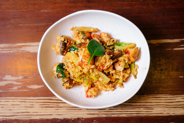 Vegetables stir fry with rice and egg. Pan-Asian oriental cuisine on wooden table.
