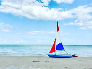 Naklejka premium Photo of boat with colorful sails on white sand beach at cloudy weather in north Germany