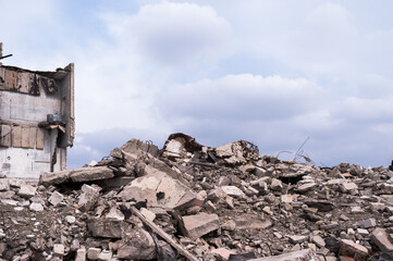 A pile of concrete fragments of construction debris against the background of the remains of the...