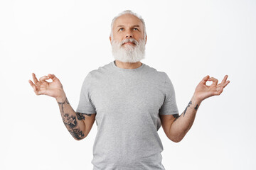 Peaceful senior man feel zen, meditating and resting, breathing calm and looking up, smiling...