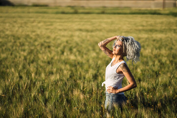 Chica con el pelo muy rizado posando en un campo de trigo