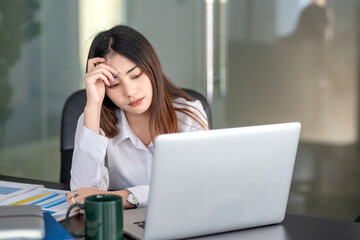 Asian businesswoman who is tired of working on a laptop at the office.