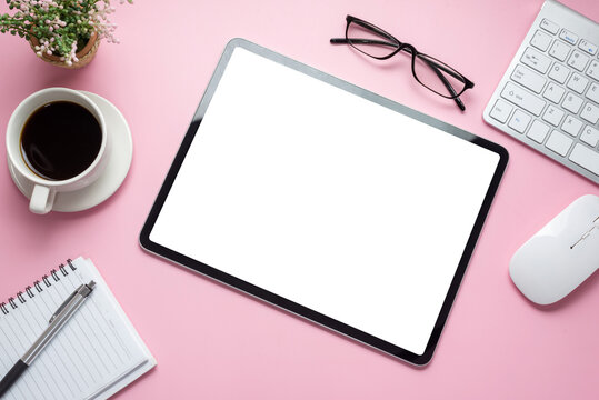 Mock up. Digital tablet blank white screen on the desk pink background.