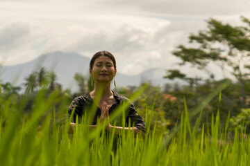 Naklejka na ściany i meble artistic portrait of young attractive and happy Asian woman outdoors at green rice field landscape dancing and doing yoga relaxation exercise and meditation 
