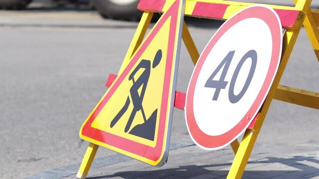 4k stock video footage of several warning and regulation road signs on road or sidewalk. Round sign indicating 40 as speed limit. Beware traffic constructions. Roadworks ahead concept