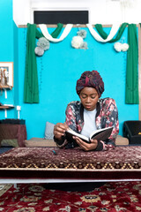 Fototapeta na wymiar Black Muslim Woman studying in blue room