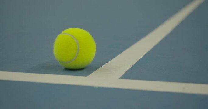 Shooting a yellow tennis ball on a blue background. Sports equipment for shops. Active leisure. Close-up. Slow motion. High quality. 4k footage.