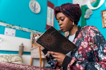 Black Muslim Woman studying in blue room - obrazy, fototapety, plakaty