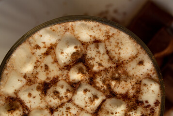 a cup of hot drink, with marshmallows, chocolate and cinnamon. 