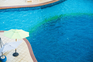 Top view big swimming pool at the edge of the pool side non slip tiles. Stick with the pool stairs. In the summer and clean water is blue deep and shallow for children and adults on vacation in hotel.