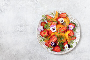 Obraz na płótnie Canvas Fresh salad with strawberries, Loquat fruit and edible flowers in a bowl