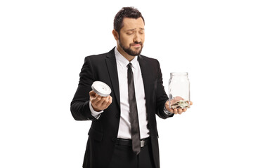 Sad businessman holding a glass jar with coins