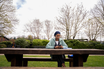 Fototapeta premium Black Muslim woman in park writing