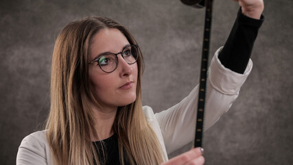 Young pretty woman looks at a film strip - studio photography