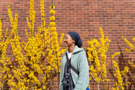 Black Muslim woman next to yellow flowers
