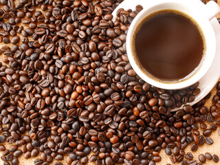 A lot of coffee beans are around hot aromatic coffee cup