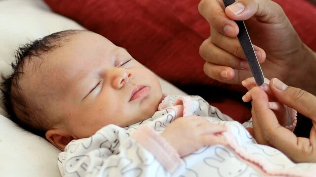 Un b&eacute;b&eacute; dort pendant que sa maman lime ses ongles