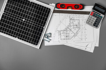 Architectural blueprints and solar panel on table