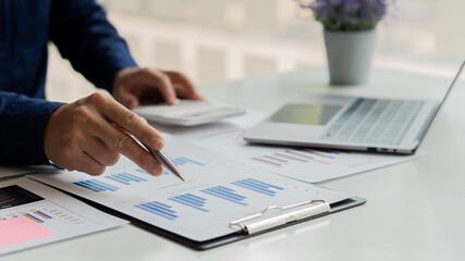 Financial business people calculate with a calculator and graph the cost of investing in real estate.