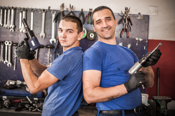 Funny workers. Car mechanic posing with their tools in workshop