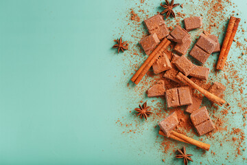 Milk chocolate with spices and cocoa on a green background.