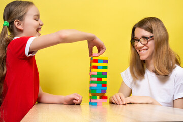 A happy family playing a round of game removing wooden blocks from tower with their lovely...