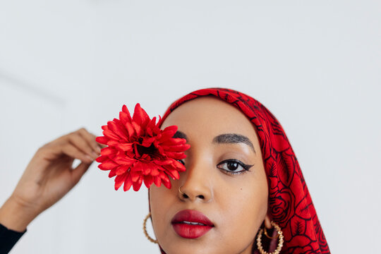 Black Muslim Woman wearing a red hijab with a red flower