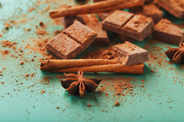 Milk chocolate with spices and cocoa on a green background.