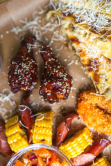 Food set of fried chicken wings, burger, fried potatoes, cheese, corn, sauce, salad