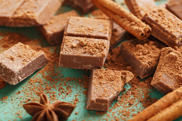 Milk chocolate with spices and cocoa on a green background.