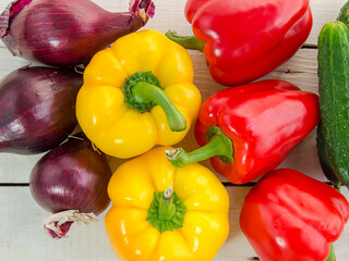 Bell pepper, red onion, cucumber on a white, wooden table. Natural ingredients for salad. Vegan, healthy food. Summer harvest.