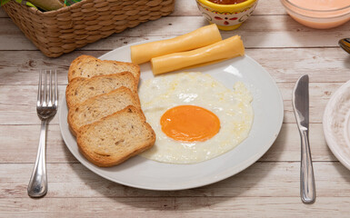 Fried egg with slices of cheese and toast on a rustic farm table