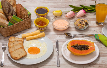 Breakfast on the farm with jams, toast, eggs, fruit, cereals, juice, milk and coffee on a rustic wooden table