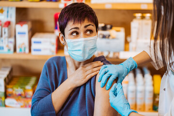 Young woman receiving the vaccine for the virus caused by covid 19 with a face of pain. Fear and worry.