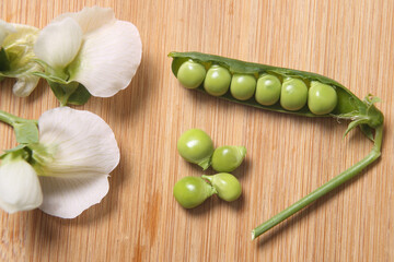 Legumes - The pod of peas with the white flower typical of the pea plant placed on the wooden tray