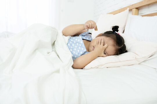 Cute little Asian toddler girl tired and sleepy in bed