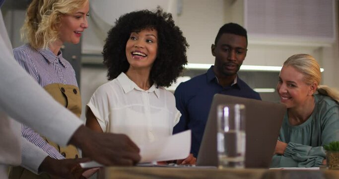 Diverse group of business colleagues talking in a meeting room smiling applauding