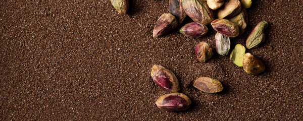 Pistachio nuts on brown textured sand  background