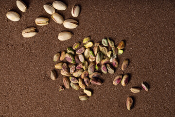 Pistachio nuts on brown textured sand  background